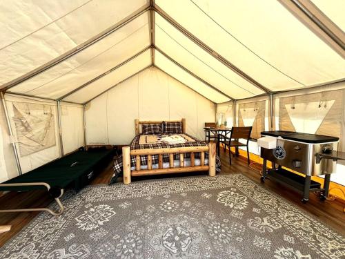 Cute and Comfortable Safari Tent in Seward, Alaska - Amazing Glamping Accommodation with Breathtaking Mountain Views في Bear Creek: غرفة نوم في خيمة مع سرير وطاولة