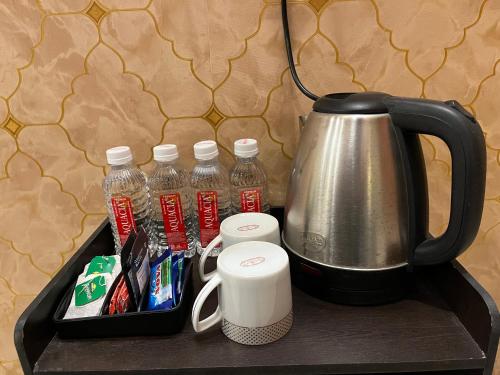 a tray with a tea kettle and bottles of water at Golden Lotus Varanasi in Varanasi