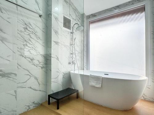 a bathroom with a white tub and a window at 提供免费汽车使用的含泳池被墅房间 in Chiang Mai