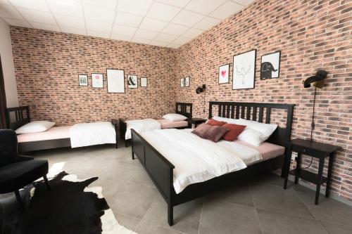 a bedroom with three beds and a brick wall at Apartments NESTL in Ptuj