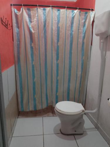 a bathroom with a toilet and a shower curtain at Casa pertinho do centro in Pipa