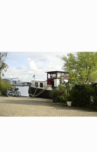 a boat is parked next to the water at B&B Teddy "Prachtig authentiek woonschip uit 1912, 15 minuten van Amsterdam" in Wormer