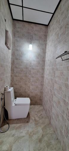 a bathroom with a toilet and a brick wall at Safari Eye Hotel - Thissa in Debarawewa