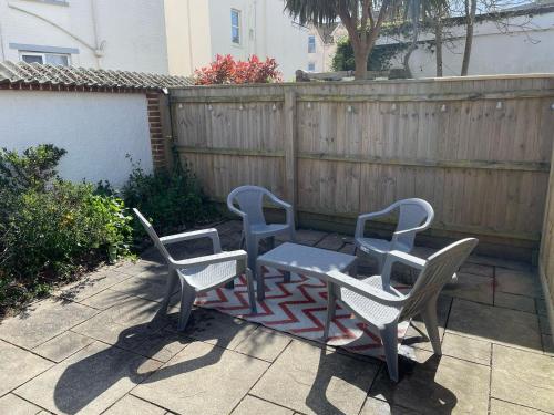 three chairs and a table on a patio at Stylish home with garden near the beach in Bournemouth