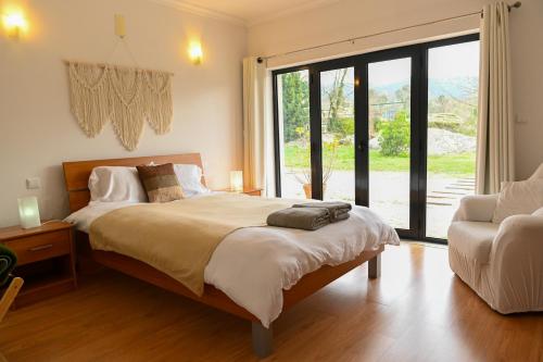 a bedroom with a bed and a chair and a window at Fabulous 5 BR hidden gem Serra da Estrela in Vinhó