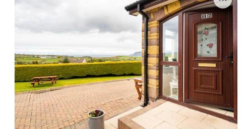 a door to a building with a bench on a patio at Cullentra House in Cushendall