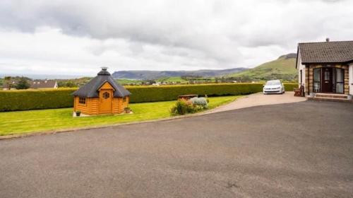 a small house with a car parked next to a driveway at Cullentra House in Cushendall