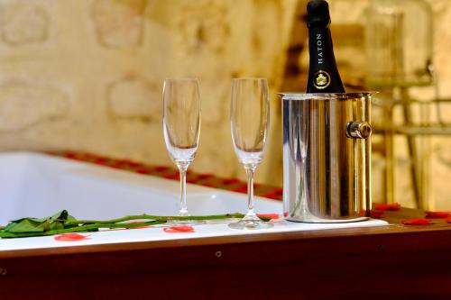 two champagne glasses and a champagne bottle in a bucket at L'Autel La Crypte Mystérieuse de Rouen - sauna & balnéo in Rouen