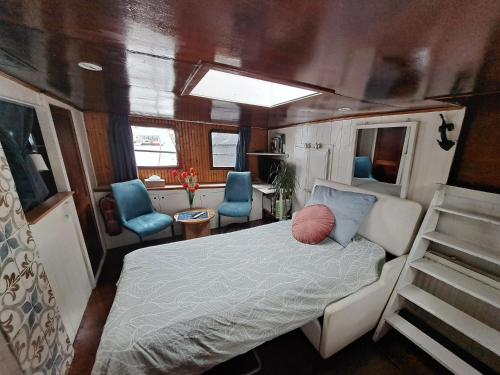 a bedroom with a bed and two blue chairs at B&B Teddy "Prachtig authentiek woonschip uit 1912, 15 minuten van Amsterdam" in Wormer