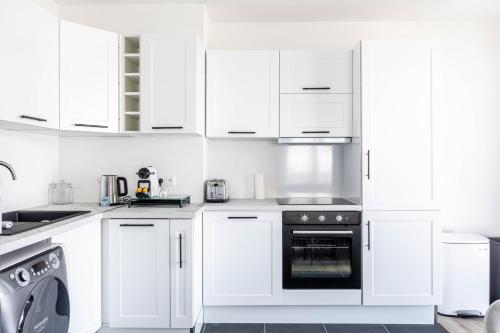 - une cuisine blanche avec des placards blancs et un lave-vaisselle dans l'établissement GuestReady - Sunny Retreat Minutes from Paris, à Aubervilliers