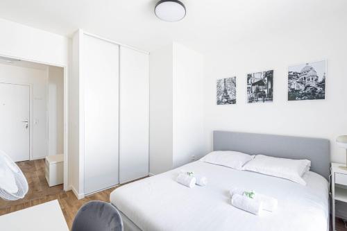 une chambre blanche avec un lit et une chaise dans l'établissement GuestReady - Sunny Retreat Minutes from Paris, à Aubervilliers