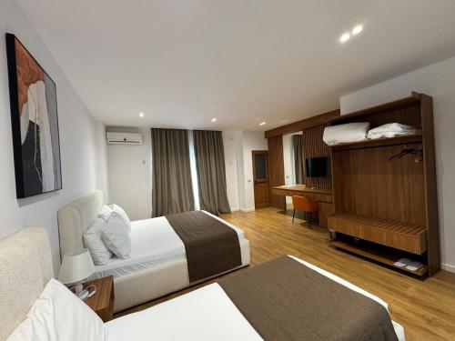 ein Hotelzimmer mit zwei Betten und einem Schreibtisch in der Unterkunft ORCHIDS Hotel in Sarandë
