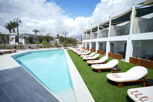 a hotel with a pool with lounge chairs next to it at Blue Harbour Boutique in Ayia Napa