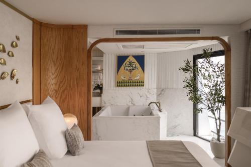 a bedroom with a bath tub and a bed with white sheets at Soleil Nile Cruise - Every Monday from Luxor for 4 & 7 Nights, and every Friday from Aswan for 3 & 7 Nights in Luxor