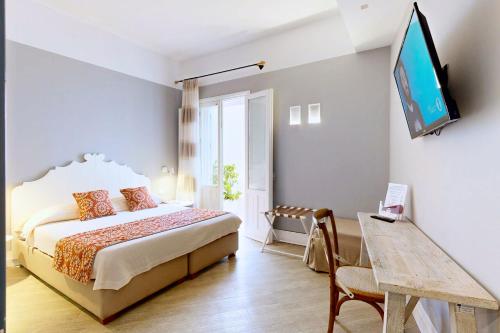 a bedroom with a bed and a tv on a wall at Aegusa Hotel in Favignana
