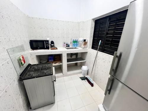 a small kitchen with a stove and a refrigerator at Résidence Khadija Aéroport AIBD Confort in Rufisque