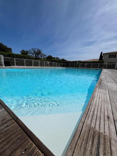 une piscine d'eau bleue et une terrasse en bois dans l'établissement Mini villa,, 700 m de la plage à pieds, à Pinarellu