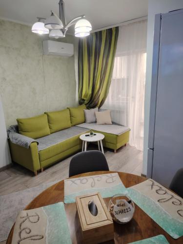 a living room with a green couch and a table at RELAX Downtown Suite in Constanţa