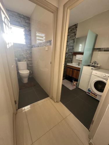 a bathroom with a toilet and a washing machine at Zenith by Proxima Homes in Lautoka