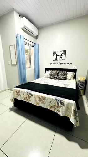 um quarto com uma cama grande e cortinas azuis em Cantinho Aconchegante in Foz em Foz do Iguaçu