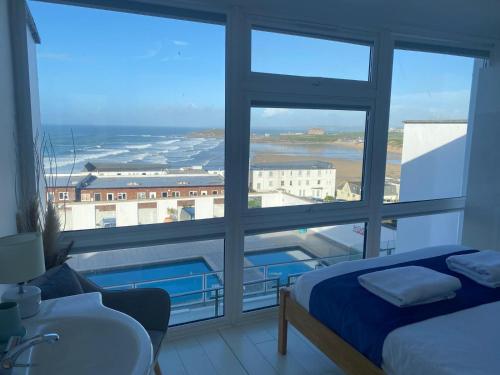 a room with a large window with a bed and a sink at Stunning Sea View Apartment in Newquay with a Pool in Crantock