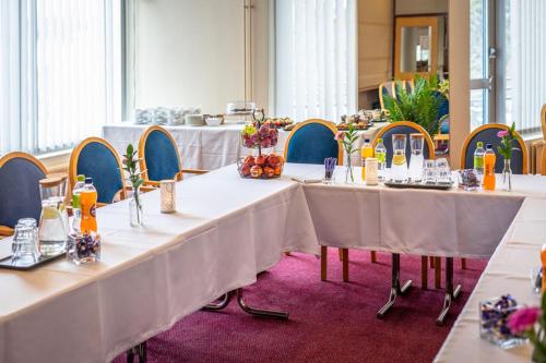 a group of tables with white table cloths in a room at Hotel Kurikka in Kurikka