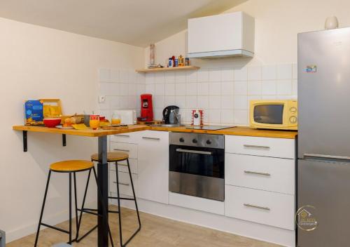 a kitchen with white cabinets and a counter with a microwave at Le refuge du canal Local à vélo Face canal du midi in Castelnaudary