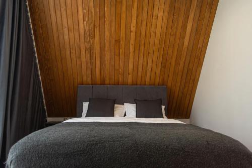 a bedroom with a large bed with a wooden wall at AVA Chalet in Comarnic