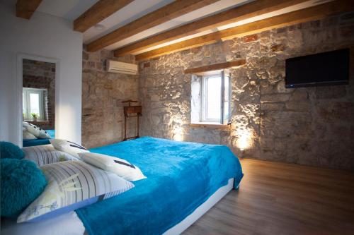 a bedroom with a blue bed and a stone wall at Villa Veli Varos in Split