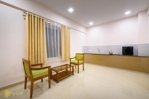 a room with two chairs and a table and a tv at Daffodils Luxury Airport Suites in Cochin