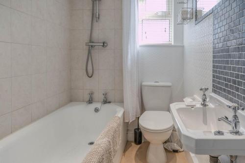 a bathroom with a tub and a toilet and a sink at Strand Cottage - Sheringham - Crabpot Cottages Sheringham in Sheringham