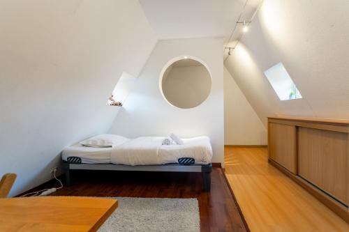 - une chambre avec un lit et un miroir rond dans l'établissement Le Cocon Alsacien, à Strasbourg