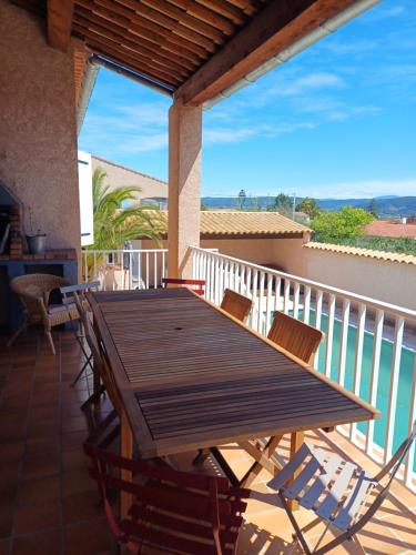 d'une terrasse avec une table et des chaises en bois sur un balcon. dans l'établissement Côté Provence - Côté Piscine, à Villeneuve