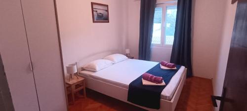 a small bedroom with a bed and a window at Aparmani Đani 2 in Pag
