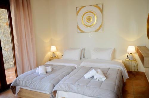 a bedroom with two beds with white sheets and towels at Malvazios Villas #3 in Gythio