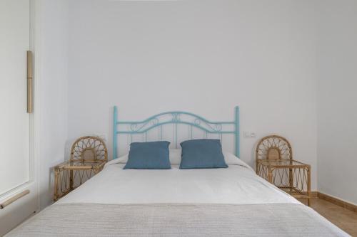 a large bed with two blue pillows on it at Casa Buganvilla in Barbate