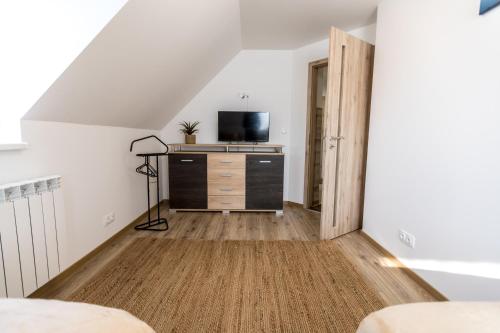 a room with a tv and a dresser in a attic at Mátravölgy Apartmanház in Pásztó