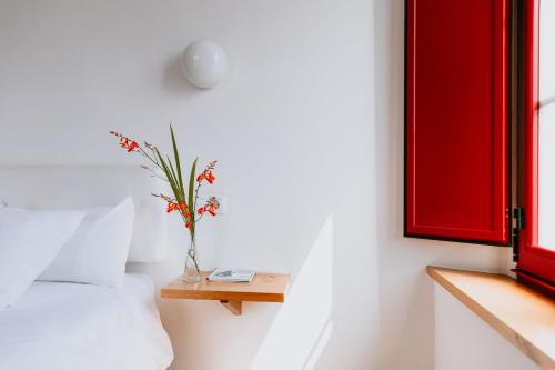 a bedroom with a bed and a vase of flowers on a table at Hotel El Castaño Dormilón in Santa Marta de Ortigueira