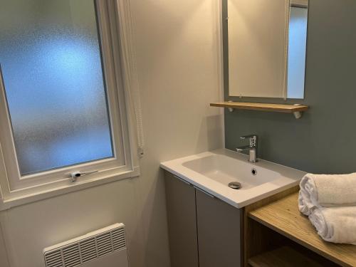 a bathroom with a sink and a mirror and a window at La petite folie in Quiberon