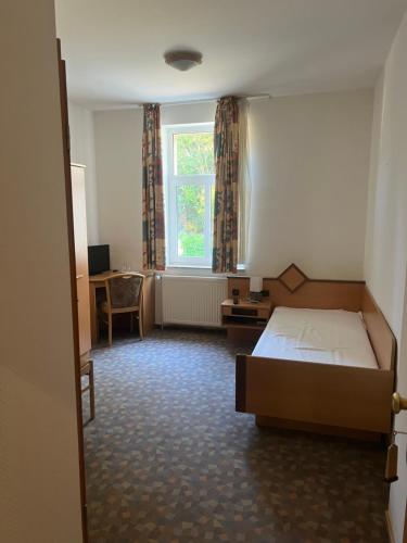 a bedroom with a bed and a desk and a window at Königszinnenberg Hotel in Bodenwerder