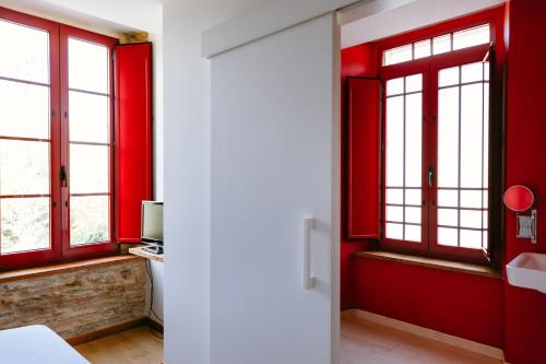 a room with red walls and windows and a bed at Hotel El Castaño Dormilón in Santa Marta de Ortigueira