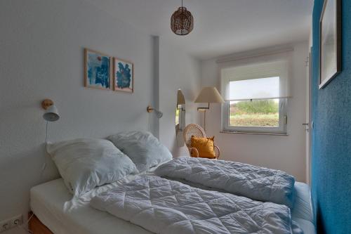 a bedroom with a bed with pillows and a window at Flunder in Börgerende-Rethwisch