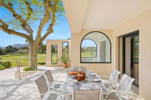 une salle à manger avec une table, des chaises et un arbre dans l'établissement La Méditerranée à vos pieds - Vue & Accès, à Carqueiranne