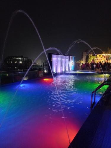 a pool with colored lights in the water at night at Hotel Elite Palace in Comilla