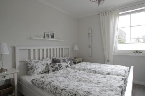Una habitación blanca con una cama y una ventana en Strandlust, en Ostseebad Nienhagen
