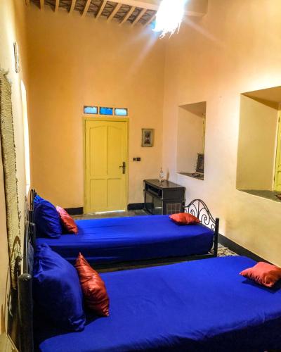 a bedroom with two beds with blue sheets and a yellow door at Dar Toda - Zagora guest house in Zagora