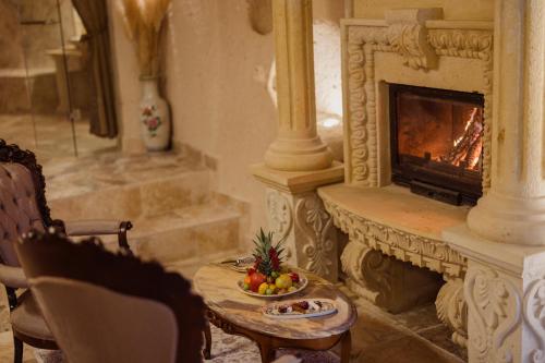 a living room with a fireplace and a table with a bowl of fruit at The Kingdom Of Cappadocia Luxury Cave Hotel in Uchisar