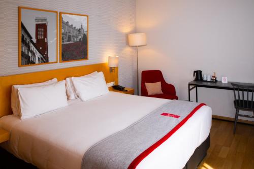 a hotel room with a large bed and a red chair at Ramada by Wyndham Madrid Getafe in Getafe