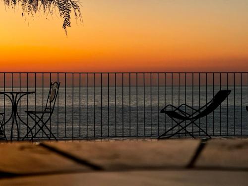 two chairs and a table on the beach at sunset at Villa Taurus Costa dei Monaci Parghelia Tropea in Parghelia