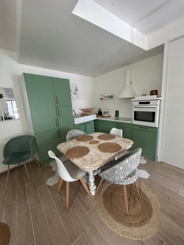 a kitchen with green cabinets and a table and chairs at Petite maison dans village animé in Jaulgonne